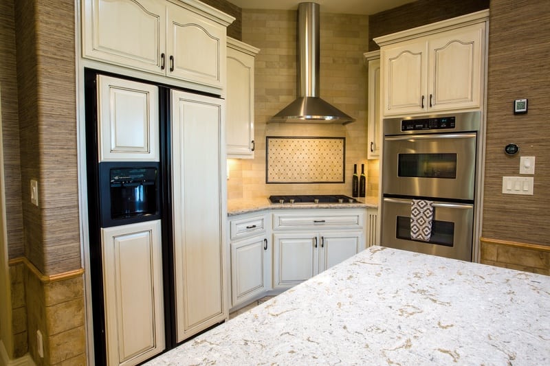 View of cabinet matching refrigerator, tile backsplash and oven